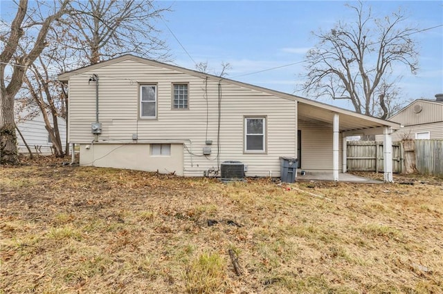 rear view of property with central AC unit and a lawn