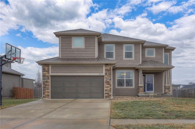 view of front of home with concrete driveway, an attached garage, a front yard, fence, and stone siding