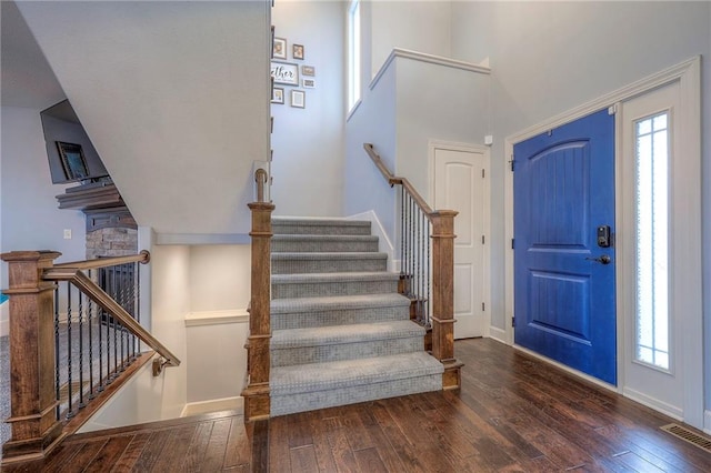 foyer entrance featuring dark wood-type flooring and a towering ceiling