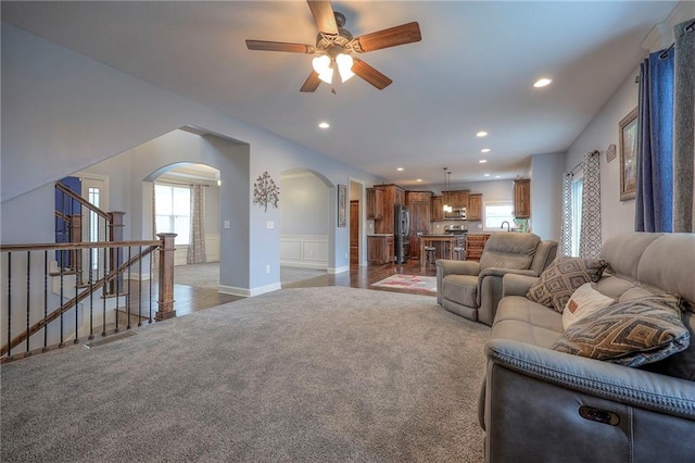 living room featuring recessed lighting, stairs, arched walkways, and light colored carpet