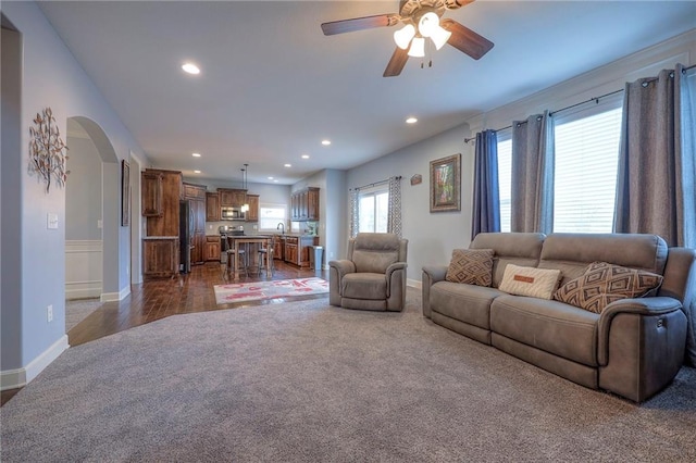 living area featuring arched walkways, dark colored carpet, a ceiling fan, and recessed lighting