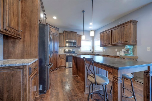 kitchen featuring stainless steel appliances, dark hardwood / wood-style floors, a kitchen island, and backsplash