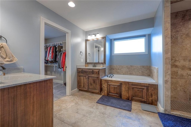 bathroom featuring a bath, a tile shower, two vanities, and a sink