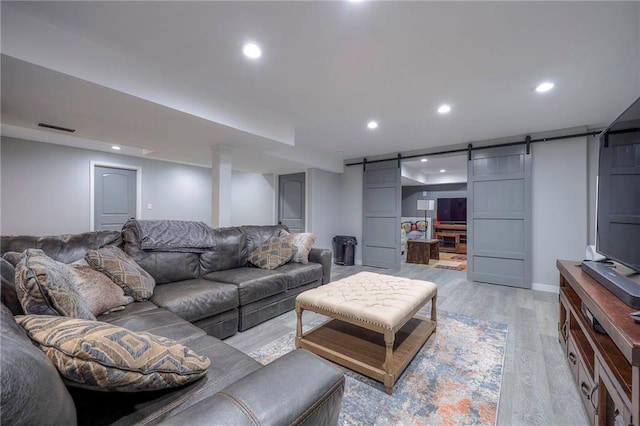 living area featuring light wood finished floors, a barn door, visible vents, and recessed lighting