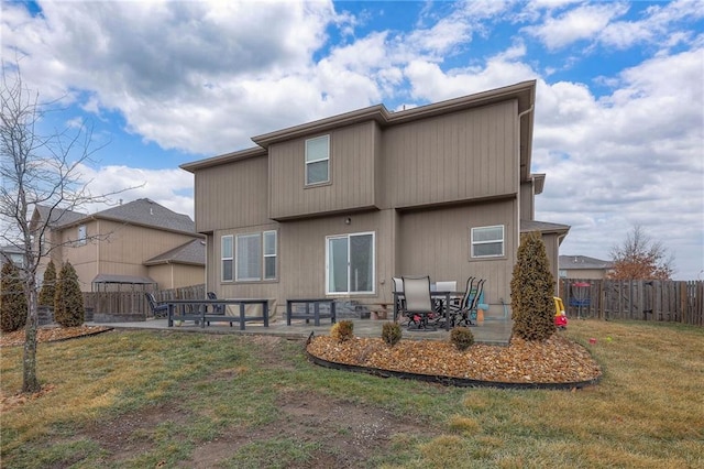 back of property with a yard, a patio, and fence