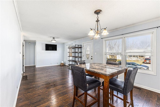 dining room with a textured ceiling, dark wood-style floors, and crown molding