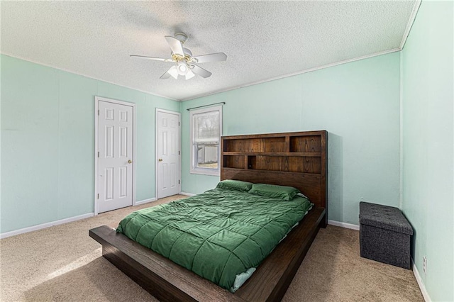 bedroom featuring baseboards, carpet floors, ceiling fan, a textured ceiling, and two closets