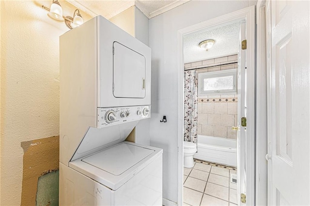 laundry room with a textured ceiling, light tile patterned flooring, laundry area, and stacked washer / dryer