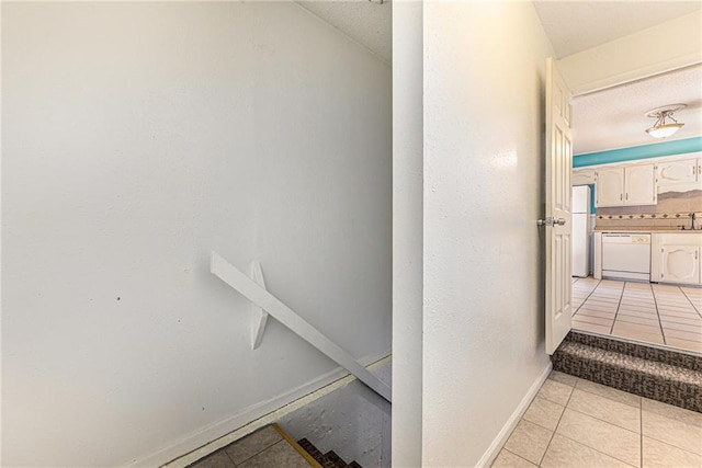 hall with light tile patterned flooring and baseboards