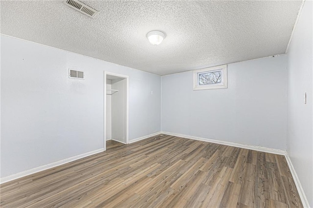 empty room featuring visible vents, baseboards, and wood finished floors