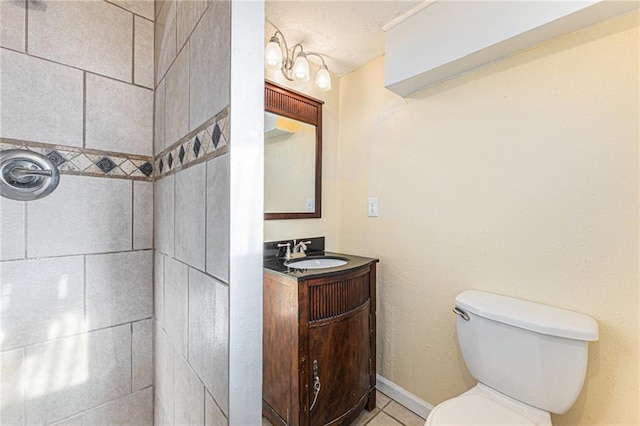 bathroom featuring tile patterned floors, tiled shower, toilet, and vanity