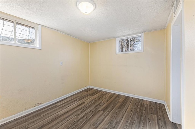 below grade area with baseboards, a textured ceiling, and wood finished floors