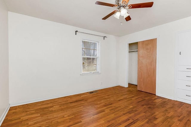 unfurnished bedroom with baseboards, a closet, visible vents, and wood finished floors