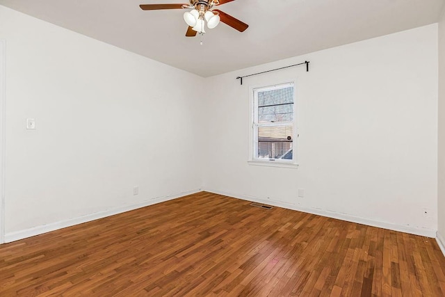 unfurnished room with ceiling fan, wood-type flooring, visible vents, and baseboards