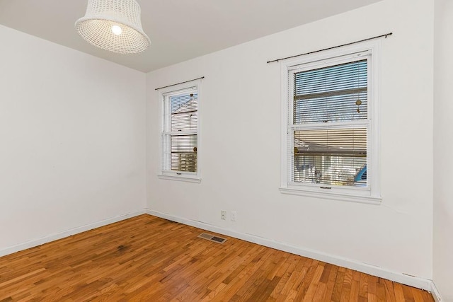 spare room with visible vents, baseboards, and wood finished floors