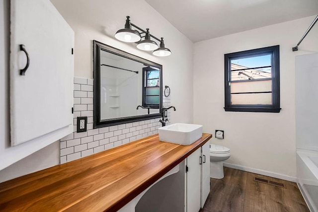 bathroom with decorative backsplash, visible vents, plenty of natural light, and toilet