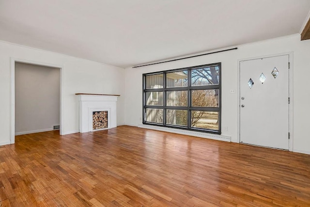 unfurnished living room featuring light wood-type flooring, visible vents, a fireplace, and baseboards