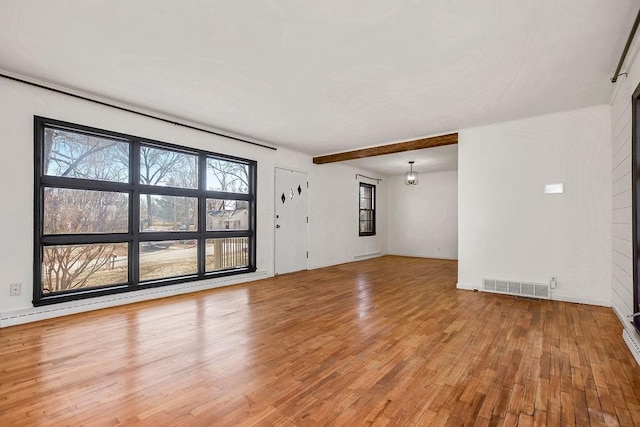 spare room with beamed ceiling, light wood-type flooring, and visible vents