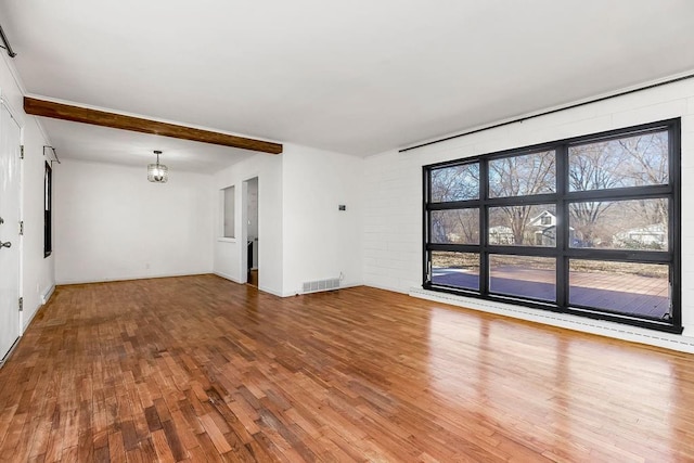 unfurnished living room featuring a notable chandelier, visible vents, wood finished floors, and beamed ceiling