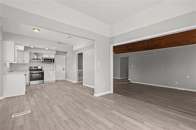 unfurnished living room with light wood-style flooring, baseboards, visible vents, and a sink