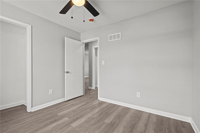 unfurnished bedroom with a ceiling fan, wood finished floors, visible vents, and baseboards