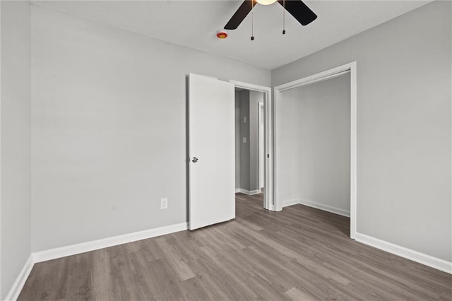 empty room featuring baseboards, wood finished floors, and a ceiling fan
