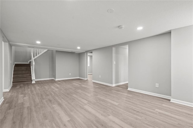 finished below grade area featuring recessed lighting, stairway, light wood-style flooring, and baseboards