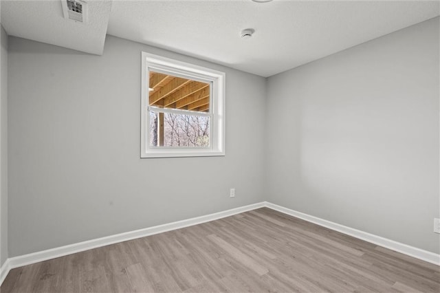 empty room featuring visible vents, baseboards, and wood finished floors