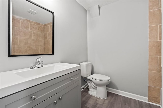 bathroom featuring baseboards, toilet, wood finished floors, and vanity