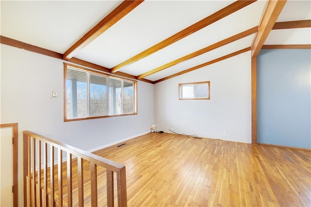 spare room with lofted ceiling with beams and light hardwood / wood-style floors