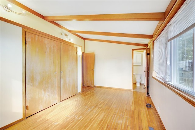 unfurnished bedroom featuring lofted ceiling with beams, light hardwood / wood-style floors, and a closet