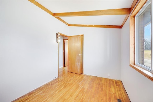 empty room featuring light hardwood / wood-style floors and lofted ceiling with beams