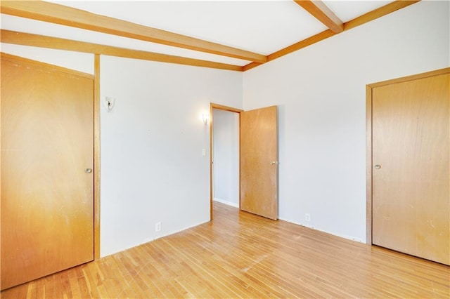 unfurnished bedroom with wood-type flooring and vaulted ceiling with beams