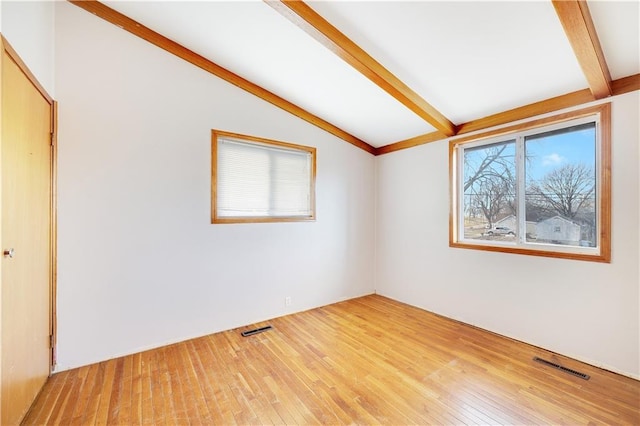 empty room featuring wood-type flooring and vaulted ceiling with beams