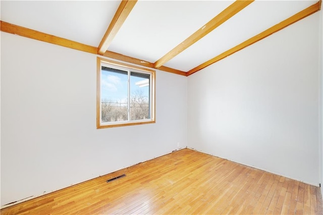 empty room with wood-type flooring and beam ceiling