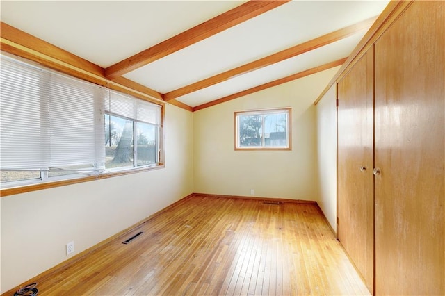 unfurnished bedroom featuring lofted ceiling with beams, a closet, and light hardwood / wood-style flooring