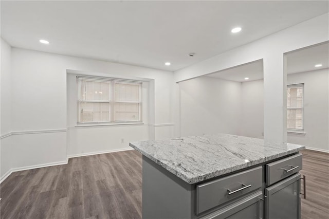 kitchen with dark hardwood / wood-style floors, light stone countertops, and a kitchen island