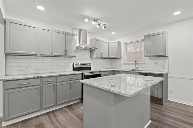 kitchen with wall chimney range hood, sink, gray cabinetry, electric range, and a kitchen island