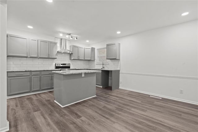 kitchen featuring wall chimney exhaust hood, gray cabinetry, tasteful backsplash, a center island, and dark hardwood / wood-style flooring