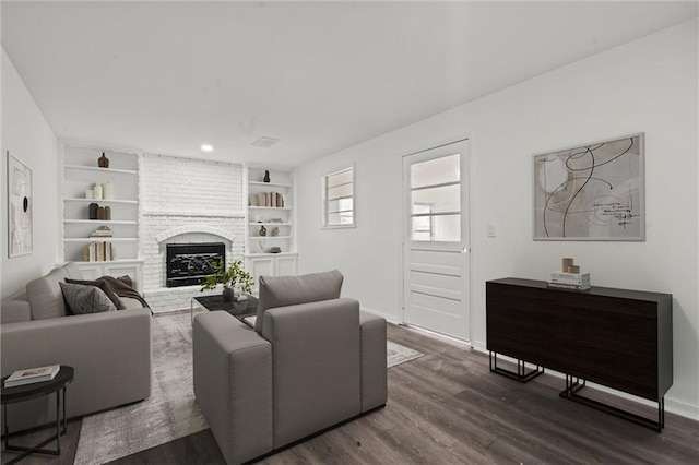 living room featuring a brick fireplace, dark hardwood / wood-style floors, and built in shelves