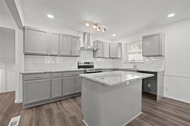 kitchen featuring dark wood-type flooring, a sink, stainless steel range with electric cooktop, gray cabinets, and wall chimney exhaust hood