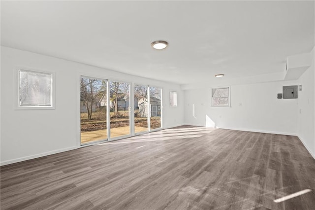 unfurnished living room with wood finished floors, electric panel, and baseboards