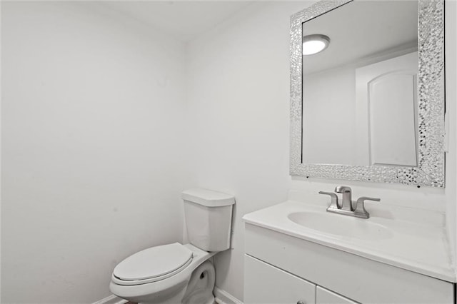 half bathroom with vanity, toilet, and baseboards