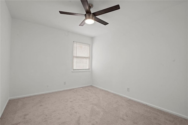 spare room with carpet, a ceiling fan, and baseboards