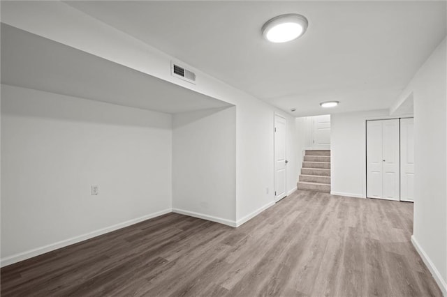 finished below grade area with visible vents, stairway, baseboards, and wood finished floors