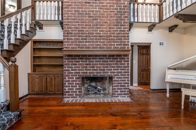 living room with a brick fireplace and dark wood-type flooring