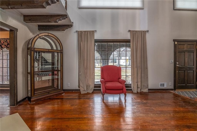 sitting room featuring a towering ceiling and dark hardwood / wood-style floors