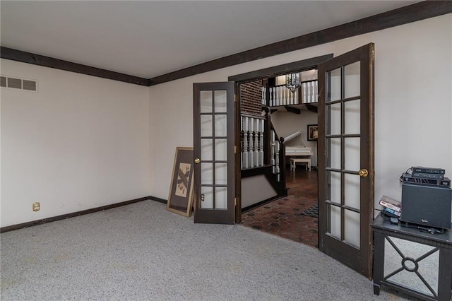 carpeted spare room featuring french doors and a chandelier