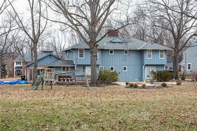 rear view of house featuring a wooden deck, a playground, and a lawn