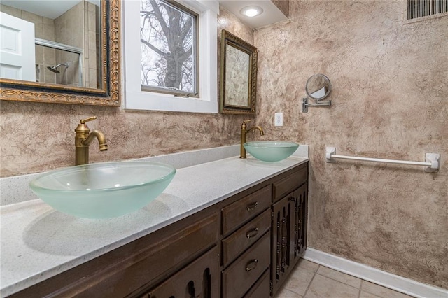 bathroom with walk in shower, vanity, and tile patterned flooring